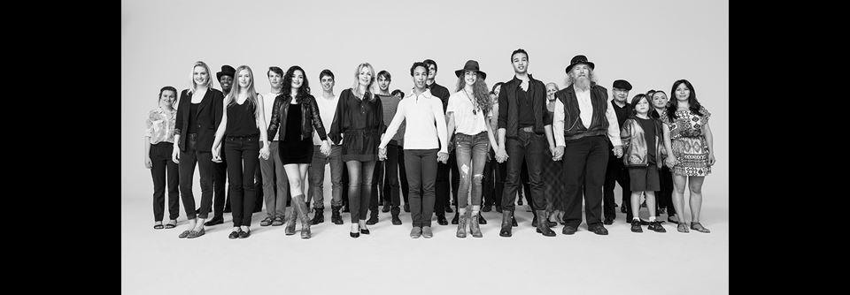 group of people holding hands and standing while looking directly at the camera