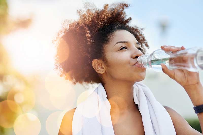 young woman drinking water after working out