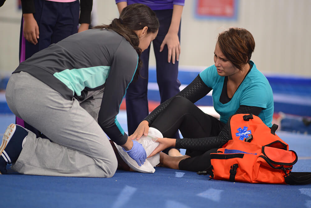 woman performing first aid for an ankle injury