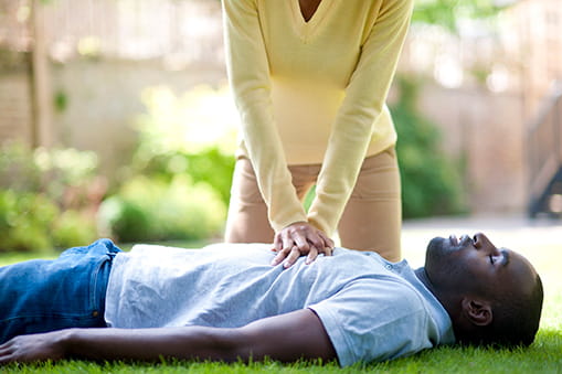 Bystander in yellow shirt attempting CPR rescue of man in blue shirt