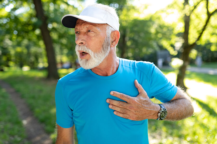 senior man with chest pain in a park