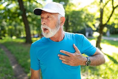 senior man with chest pain in a park senior man with chest pain in a park