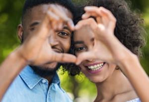 man and woman forming heart using hands