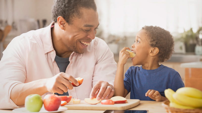 father and son eating apples in kitchen