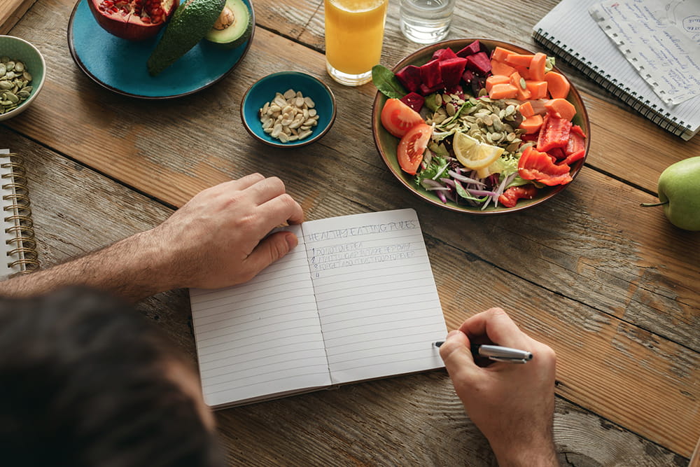 man planning meals at table with food