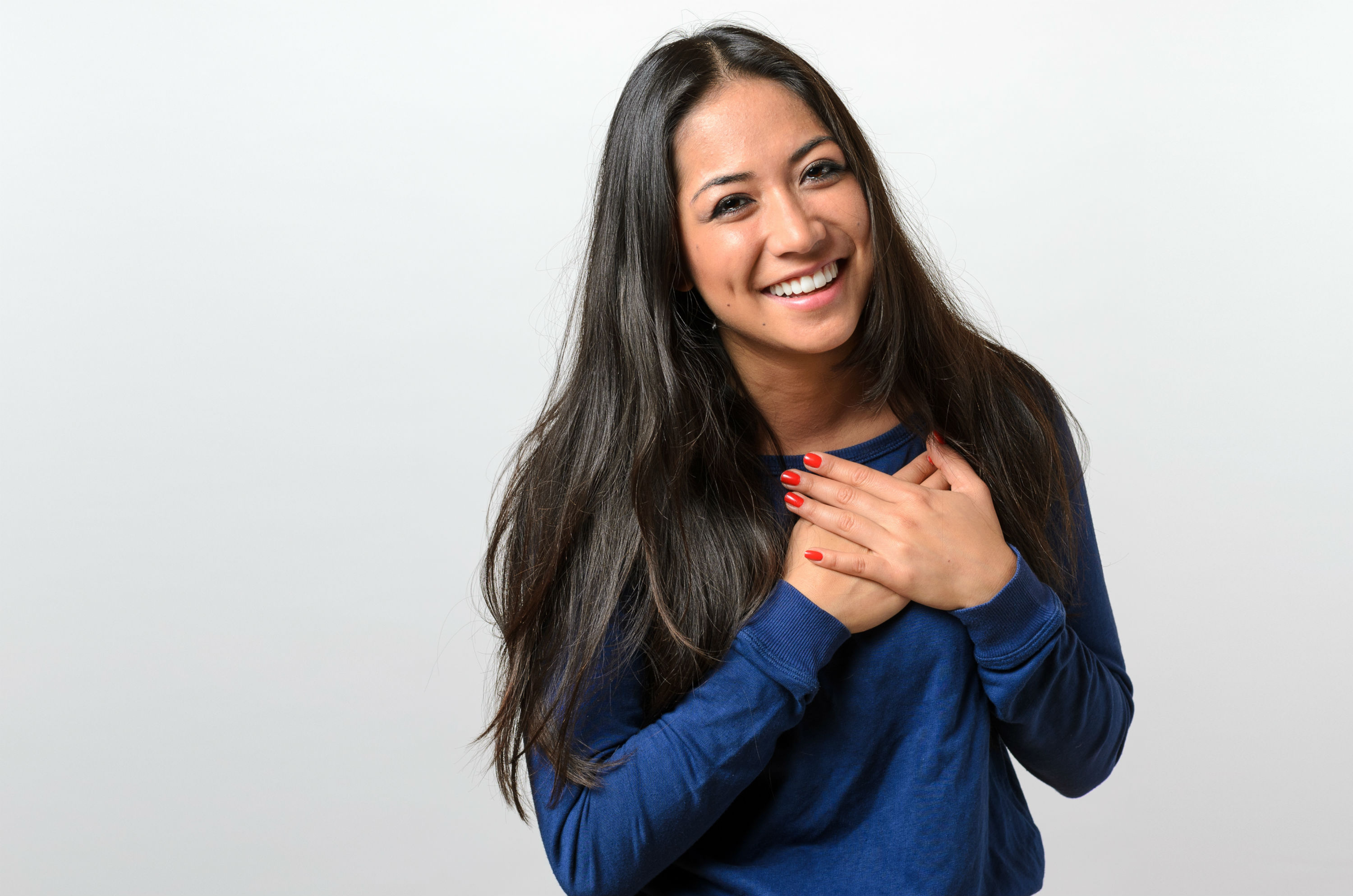 Smiling young woman with hands over heart showing gratitude