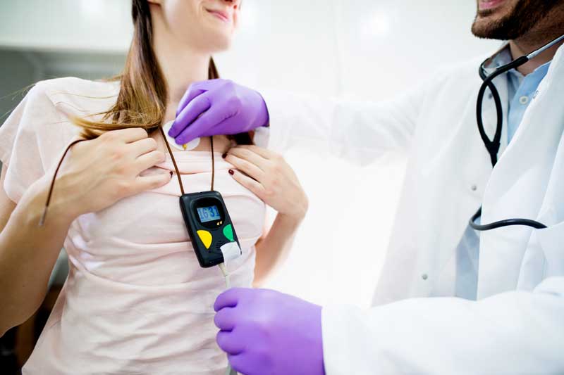 doctor putting holter monitor on patient