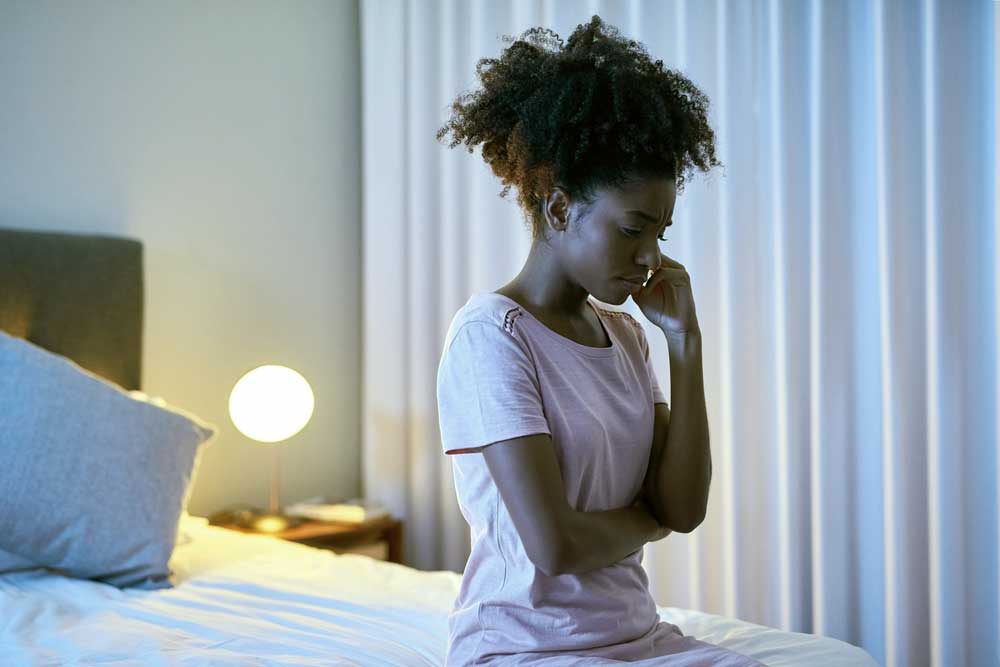 frustrated woman sitting on her bed