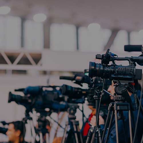 cameras on tripods lined up at press event