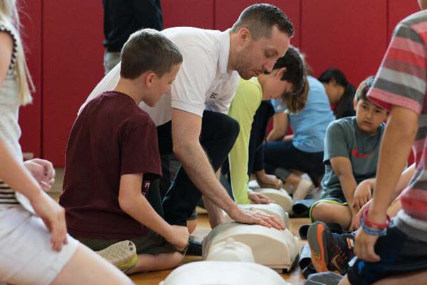 woman showing students how to perform CPR on inflatable manikin