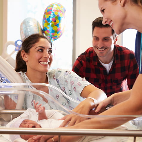 woman holding baby and father viewing them image 475x475